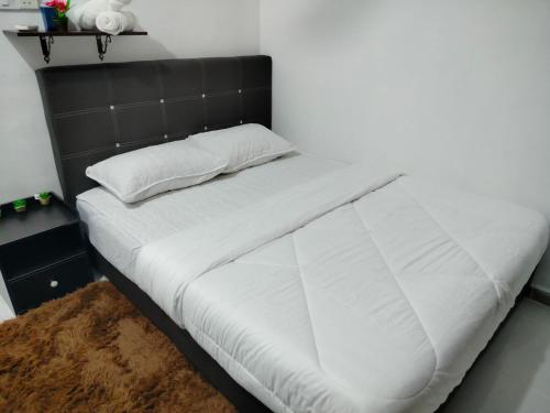 un letto con lenzuola bianche e una testiera nera di MyHomestay07 a Kangar