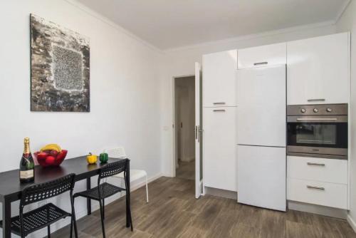 a kitchen with white cabinets and a black table and chairs at Anglesos in Can Picafort