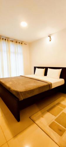 a bedroom with a large bed with a large window at Moon Plains Luxury Apartments in Nuwara Eliya