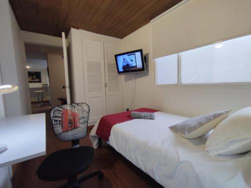 een slaapkamer met een bed, een stoel en een televisie bij Habitación sencilla con baño privado Unicentro in Bogota