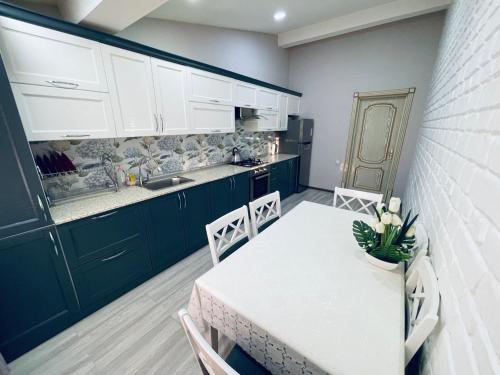 a kitchen with a white table and chairs and a counter at Aleksandra Apartment in Samarkand