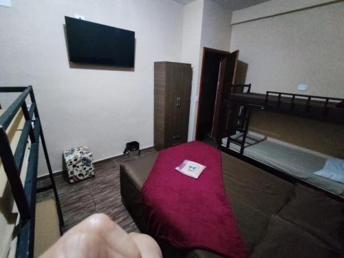 a room with a bed and a tv on the wall at Hostel Aeroporto in Guarulhos