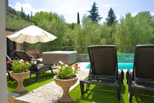a patio with chairs and an umbrella and a pool at Hotel Diffuso Il Portichetto sulla collina a Vezio Perledo in Perledo