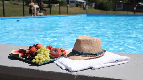 a plate of fruit with a hat next to a swimming pool at AZUR Camping Schwäbische Alb in Sonnenbühl