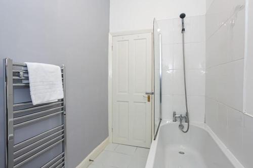 baño blanco con ducha y puerta blanca en Pillo Rooms - Spacious Cosy 2 Bedroom House by Bridgewater Canal en Mánchester