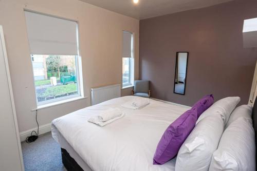 um quarto com uma grande cama branca com almofadas roxas em Pillo Rooms - Spacious Cosy 2 Bedroom House by Bridgewater Canal em Manchester