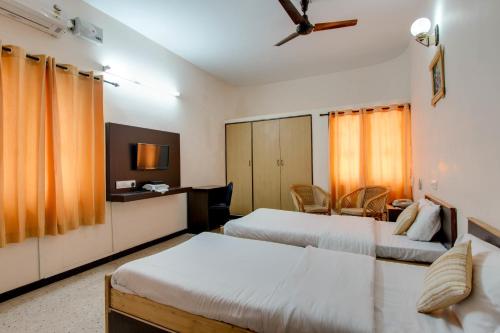 a hotel room with two beds and a tv at Corner Stay Serviced Apartment-Racecourse in Coimbatore