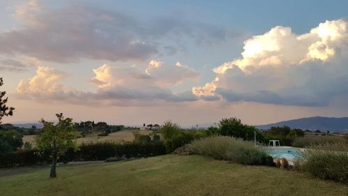 una piscina en un campo con un cielo nublado en Villa di Elisabeth, en Marciano Della Chiana