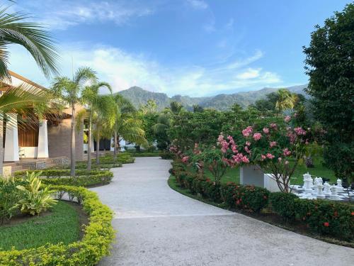 una pasarela a través de un jardín con flores y palmeras en Paraiso Rainforest and Beach Hotel, en Omoa