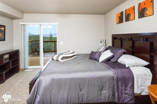 a bedroom with a large bed and a balcony at Tranquil Stay at Settlers Bay, Newly Furnished! in Wasilla