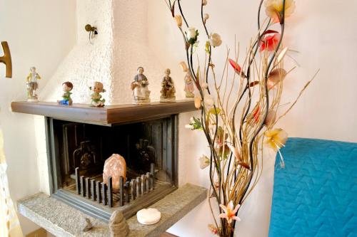 a living room with a fireplace and a vase with flowers at Hotel Diffuso Il Portichetto sulla collina a Vezio Perledo in Perledo