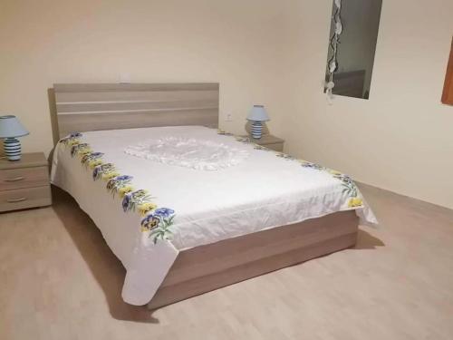 a bed with white sheets and flowers on it at Angela's place - Stomio residence near the sea in Stómion