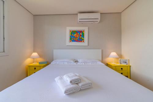 Un dormitorio con una cama blanca con toallas. en Residencial Alegro - 301, en Canela