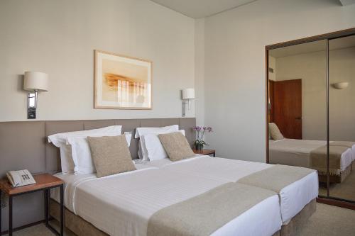 a hotel room with a large white bed and a mirror at Hotel Dom Carlos Park in Lisbon