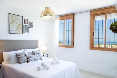 - une chambre blanche avec un lit doté de draps blancs et de fenêtres dans l'établissement Impresionantes vistas al mar en Torremolinos, à Torremolinos