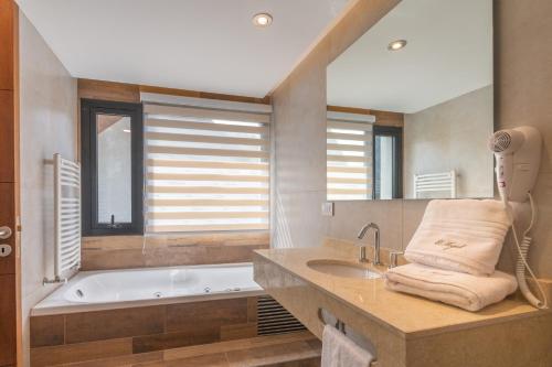 a bathroom with a tub and a sink and a mirror at El Nogal Apart Hotel in Villa General Belgrano