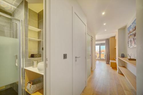 - un couloir avec une salle de bains pourvue d'un lavabo et d'un miroir dans l'établissement GHD4 - 2 pièces, Résidences du Grand Hôtel, à Cannes