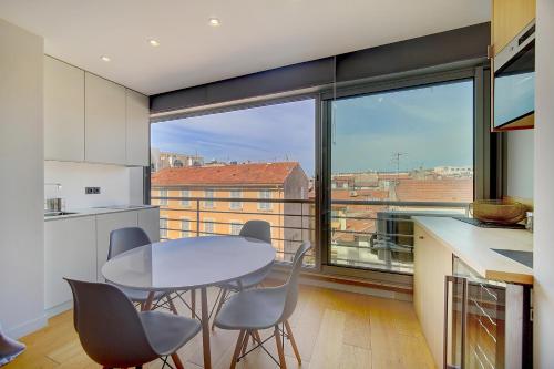 une cuisine avec une table et des chaises ainsi qu'une grande fenêtre dans l'établissement GHD4 - 2 pièces, Résidences du Grand Hôtel, à Cannes
