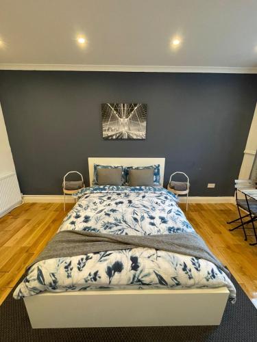 1 dormitorio con 1 cama grande y pared azul en Wembley Rooms, en Londres