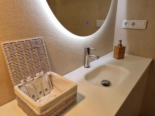 a bathroom with a sink with a mirror and a basket at C01A01 Apartamento Moderno con vistas al mar in Santander