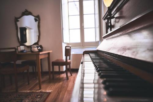 a piano in a room with a table and a window at Affittacamere San Teodoro in Albenga
