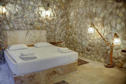 a bedroom with a bed and a stone wall at Ala Stone House in Goreme