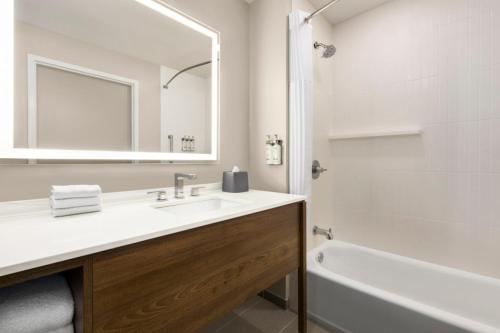 a bathroom with a sink and a tub and a mirror at Staybridge Suites - Lexington S Medical Ctr Area by IHG in Lexington