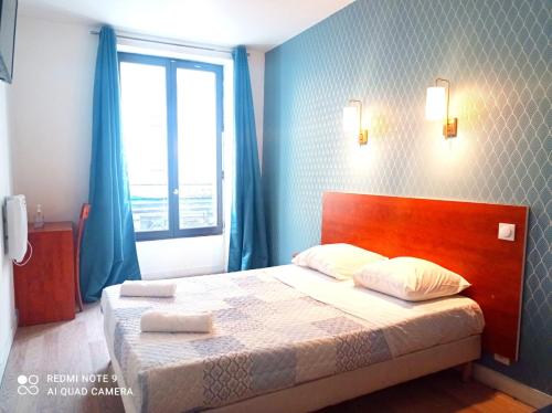 - une chambre avec un lit doté de rideaux bleus et d'une fenêtre dans l'établissement Hôtel Central Bastille, à Paris