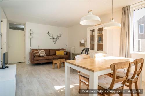 a dining room and living room with a table and chairs at Residentie Californië in De Koog