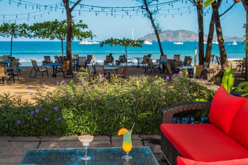 a patio with a red couch and tables and the ocean at Jet Luxury at Langosta Beach Resort & Villas in Tamarindo