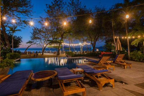 a pool at night with chairs and tables at Jet Luxury at Langosta Beach Resort & Villas in Tamarindo