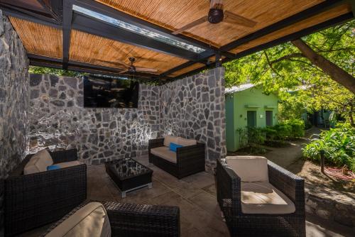 an outdoor patio with wicker furniture and a stone wall at Jet Luxury at Langosta Beach Resort & Villas in Tamarindo