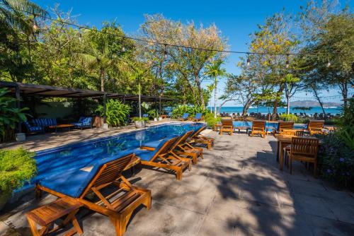 a swimming pool with wooden chairs and tables at Jet Luxury at Langosta Beach Resort & Villas in Tamarindo