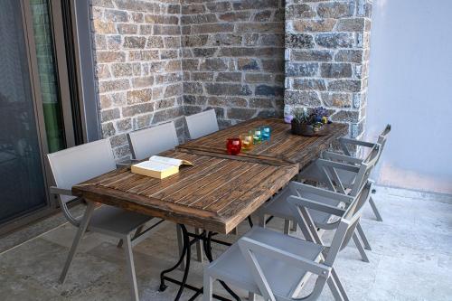 a wooden table with chairs and a brick wall at Arion Krini villa in Amnátos