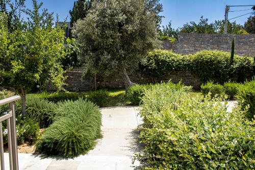 a garden with a brick wall and a tree at Arion Krini villa in Amnátos