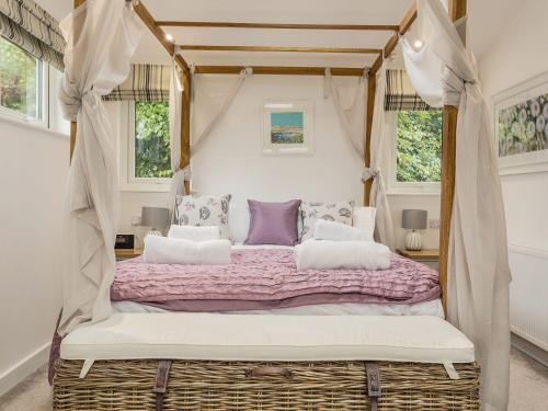 a bedroom with a canopy bed with purple and white pillows at 1 Horizon View in Liskeard