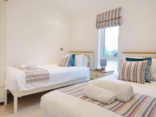 a bedroom with two beds and a window at 11 Horizon View in Liskeard