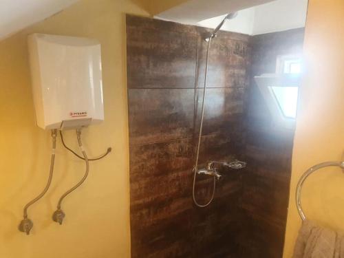een douche in een badkamer met een houten muur bij Stella del Lago Family Apartment Deluxe Penthouse in Pogradec