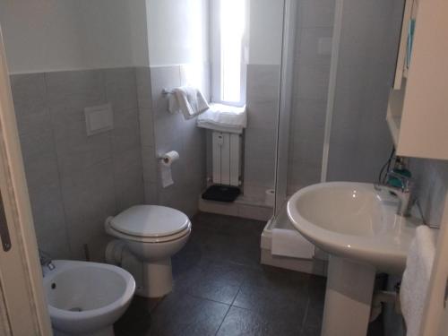a white bathroom with a toilet and a sink at B&B Gaslini & Mare (anche con uso cucina) in Genoa