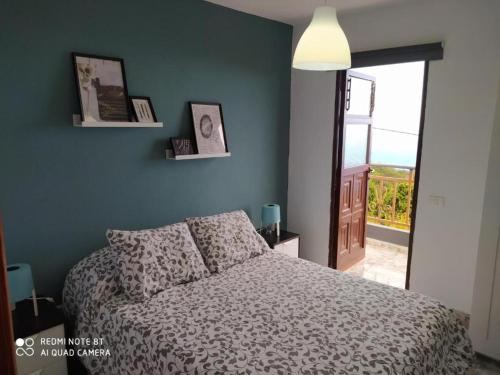 1 dormitorio con 1 cama y puerta a un balcón en Casa rural con Wifi, terraza y vistas al mar el La Palma, en Puntallana