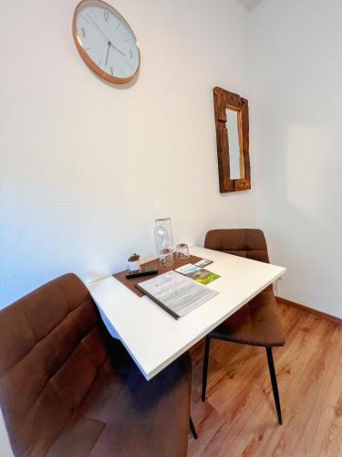 a table with a chair and a clock on the wall at Canisiusbrünnl Self- Check in in Innsbruck