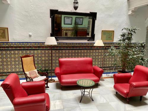 a living room with red chairs and a mirror at Pensión España in Cádiz