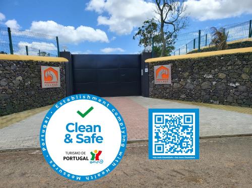 a sign that says clean and safe in front of a gate at Parrots`Village in Rabo de Peixe