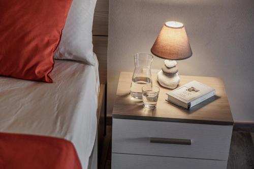 a bedside table with a lamp and a book and glasses at Siena Living Apartment in Siena