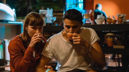 a man and a woman sitting on a bench drinking at Viajero Salento Hostel in Salento