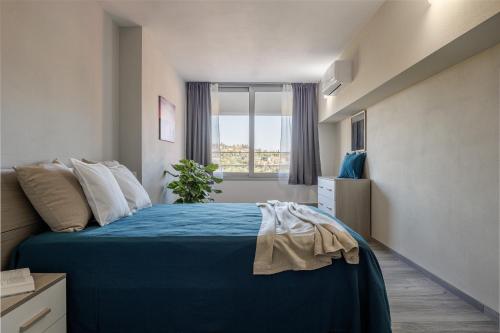 a bedroom with a blue bed with a window at Siena Living Apartment in Siena
