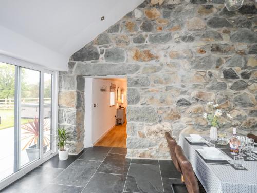 a dining room with a stone wall at Hen Felin in Pwllheli
