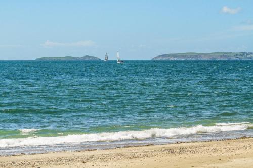 a sail boat in the ocean with a beach at Hen Felin in Pwllheli