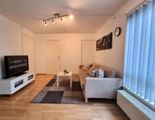 a living room with a couch and a tv at Demims Apartments Lillestrøm - Central location & Parking in Lillestrøm