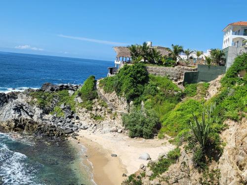 a house on a cliff next to the ocean at Hotel Luz de Mar ' right on the beach in Cuatunalco